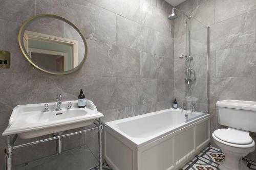 Un baño con lavabo, inodoro y espejo. en East Wing, en Thornhill