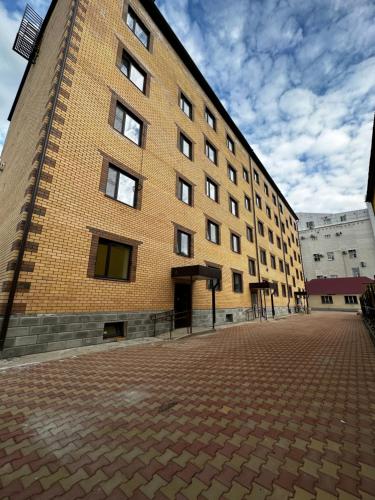 a large brick building on a brick road at Уютная квартира в центре города in Uralsk
