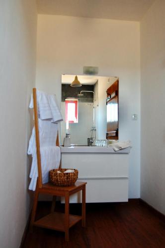 a bathroom with a sink and a mirror and a basket at Herdade da Burquilheira Family Retreat in Alcáçovas
