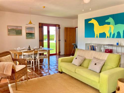 a living room with a green couch and a dining room at Herdade da Burquilheira Family Retreat in Alcáçovas