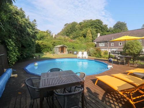 a swimming pool with a table and chairs and a picnic table at Primrose Cottage in Paignton