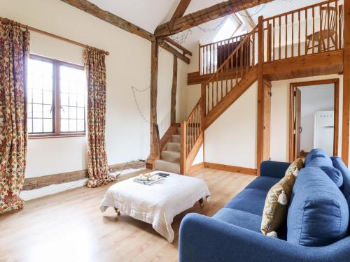 a living room with a blue couch and a staircase at Cart Wheel Cottage in Braintree