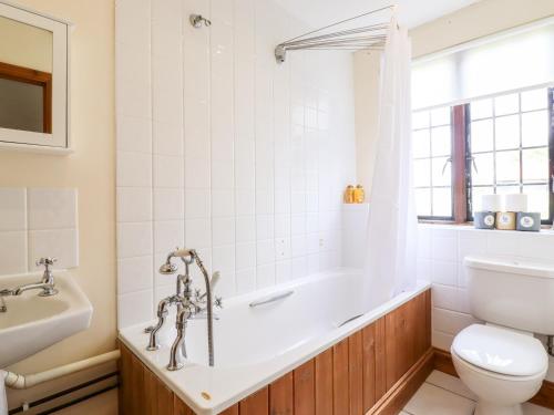 a bathroom with a tub and a toilet and a sink at Cart Wheel Cottage in Braintree