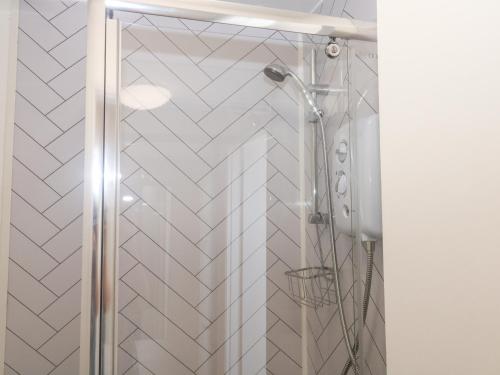 a shower with a glass door in a bathroom at Rose Cottage in Paignton