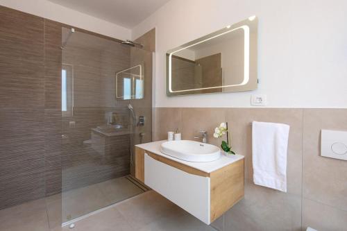 ein Bad mit einem Waschbecken, einer Dusche und einem Spiegel in der Unterkunft Villa Albina in Skrbčići