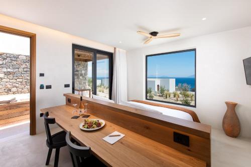 a bedroom with a desk and a bed with windows at KOIA All - Suite Well Being Resort - Adults Only in Agios Fokas