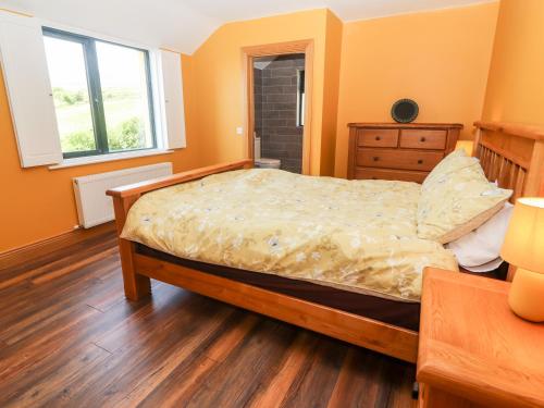 een slaapkamer met een bed en een houten vloer bij Lack Cottage in Tralee