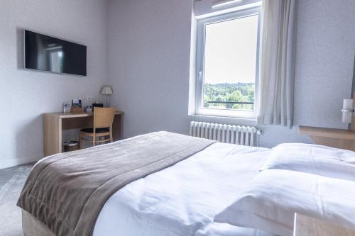 a bedroom with a large white bed and a window at Hôtel De La Plage in Le Chambon-sur-Lignon