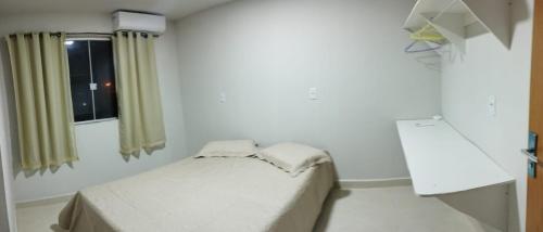 a small room with a bed and a window at Residencial Casa Grande Apto 04 in Santa Cruz Cabrália