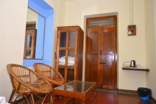 um quarto com 2 cadeiras, uma mesa e um armário de madeira em Les Boganveillea Heritage Guest House em Auroville
