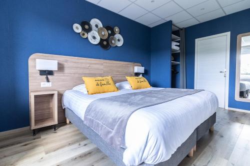 a blue bedroom with a large bed with two yellow pillows at Hôtel De La Plage in Le Chambon-sur-Lignon