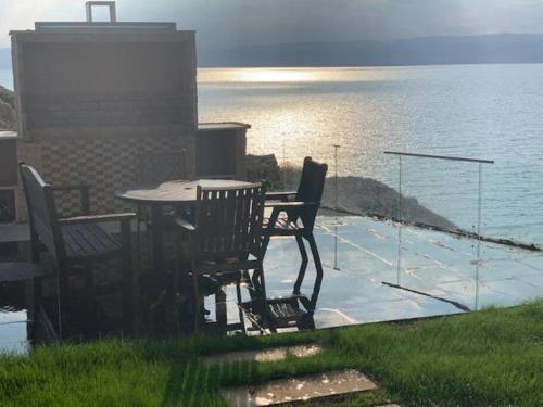 una mesa y sillas en un patio con vistas al agua en Dead Sea Jordan Sea View Samarah Resort Traveler Award 2024 winner en Sowayma
