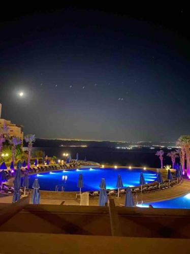 a swimming pool at night with blue lights at Dead Sea Jordan Sea View Samarah Resort Traveler Award 2024 winner in Sowayma