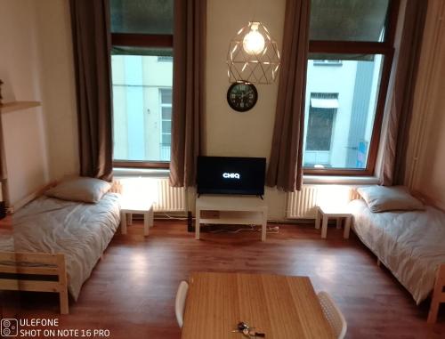 a living room with two beds and a tv at Logement Régence in Liège