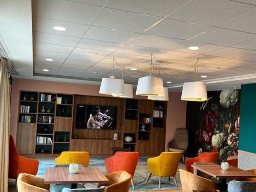 a waiting room with tables and chairs and a tv at Domitys L'Orangerie in Sens