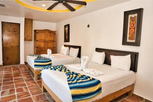 a bedroom with two beds and two chairs at Matan Kaan by GuruHotel in Mahahual