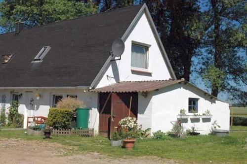 a small white house with a black roof at Ruegen_Fewo 69 in Ummanz