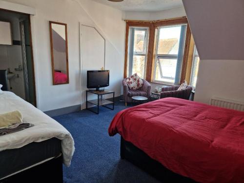 um quarto com uma cama vermelha e uma televisão em The Guest House in Sheringham em Sheringham