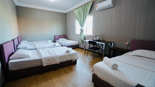 Habitación de hotel con 3 camas y escritorio. en HUAQIAO HOME 侨之家免费供早餐free breakfast served, en Semporna