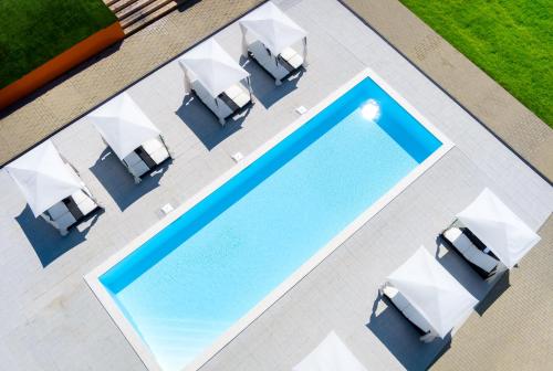 an overhead view of a swimming pool with white umbrellas and chairs at Tisza-tó Apartmanpark in Kisköre