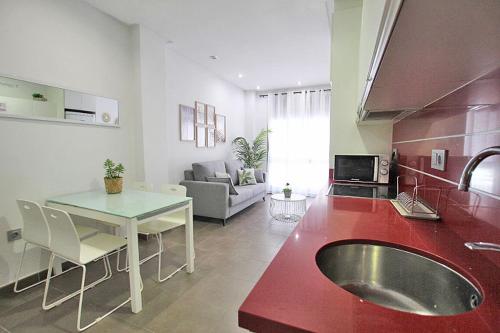 a kitchen and living room with a red counter top at Apartamento Bajo 1 Marjal playa centro de Guardamar in Guardamar del Segura