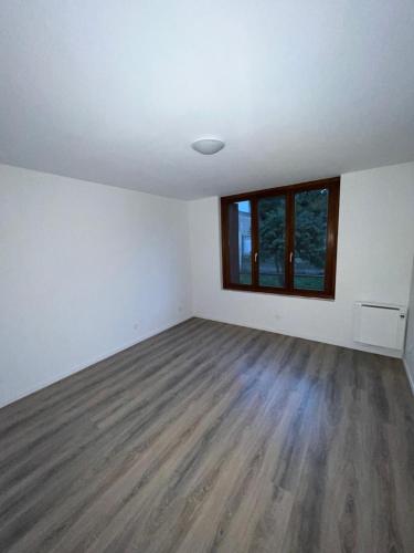 een lege woonkamer met witte muren en houten vloeren bij STUDIOS A PARTAGER in Stains