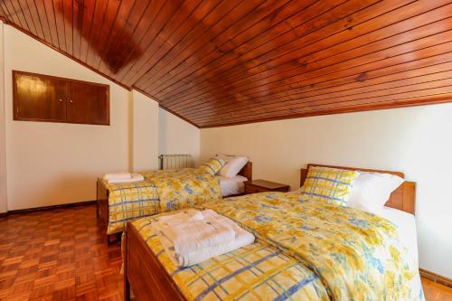 a bedroom with two beds and a wooden ceiling at Casa do Azal in Ponte de Lima