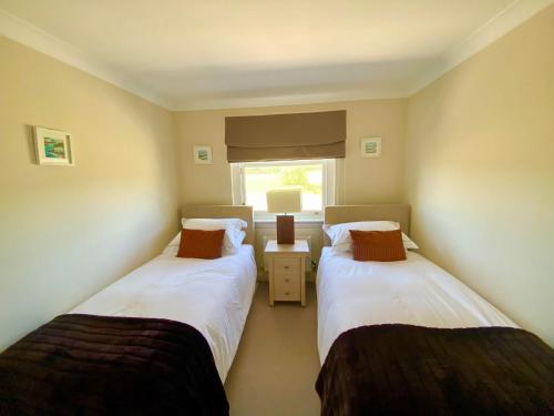 two twin beds in a room with a window at Golf Court View, Elie in Elie