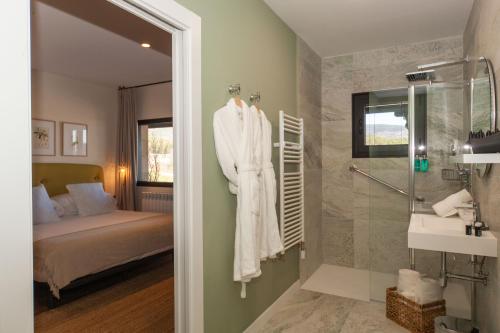 a bathroom with a robe hanging on a wall next to a bed at Duruelo Mountain Suites in Duruelo de la Sierra