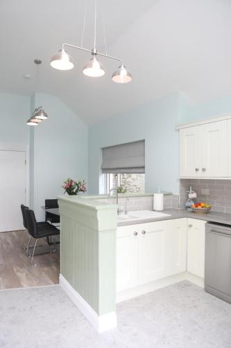 una cocina con armarios blancos y fregadero en Picturesque 3 bed house, Killala, en Killala