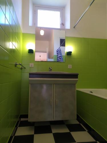 een groene badkamer met een wastafel en een spiegel bij La Haute Maison - Merrien - GR34 in Moëlan-sur-Mer