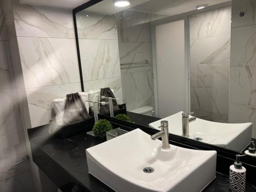 La salle de bains est pourvue d'un lavabo blanc et d'un miroir. dans l'établissement SKY INN Acapulco Y condominio mediterrane, à Acapulco