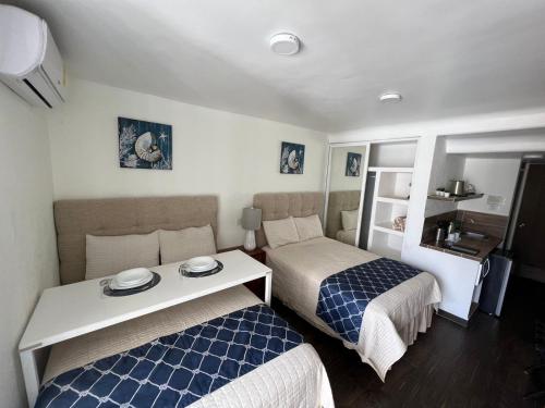 Habitación pequeña con 2 camas y mesa. en SKY INN Acapulco Y condominio mediterrane en Acapulco