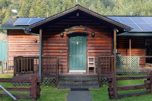 Cabaña de madera con puerta verde y porche en Elk Meadow Cabins 7 Beachcomber Studio, en Orick