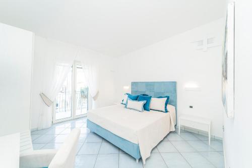 a white bedroom with a bed with blue pillows at Residenza Sant'Angelo - Art Apartment in Minori