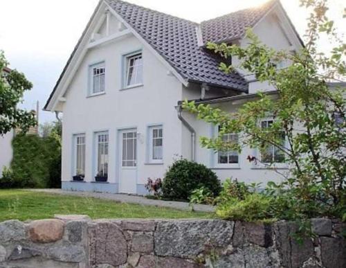 a white house with a stone wall in front of it at Ruegen Fewo 126 in Groß Zicker