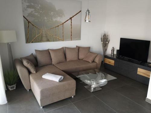 uma sala de estar com um sofá e uma televisão em FeWo Pearl 207 am Yachthafen inkl. Tiefgarage em Bremerhaven