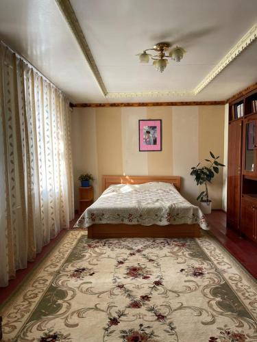 1 dormitorio con cama y alfombra grande en family homestay, en Osh