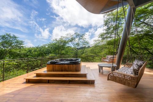 a deck with a hot tub and two chairs on a balcony at Suitree Experience Hotel in Guanacaste