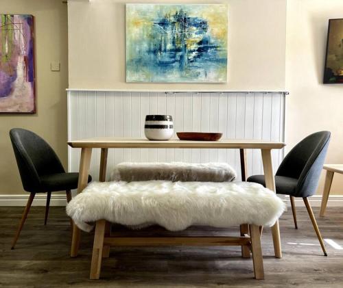 una mesa de madera con 2 sillas y un banco con un cojín blanco en The Art House 5 Galway, Bohermore en Galway