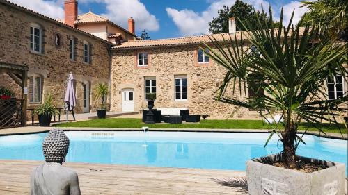una villa con una palmera frente a una piscina en Logis de la Clartière en Falleron
