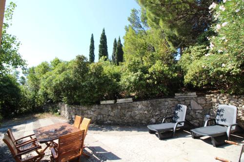 eine Terrasse mit einem Tisch, Stühlen und einer Steinmauer in der Unterkunft Makarska city center1 willa in Makarska