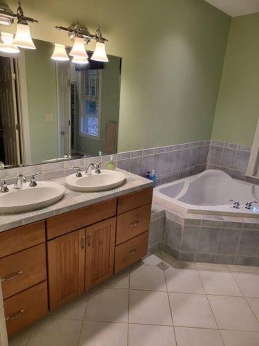 a bathroom with two sinks and a tub and a mirror at 5 Bedroom Bethel Maine home in Bethel