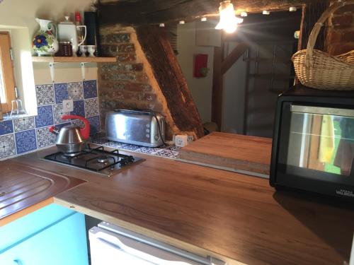 eine Küche mit einer Mikrowelle und einem TV auf der Theke in der Unterkunft Ancien Relais de Poste in Collandres-Quincarnon