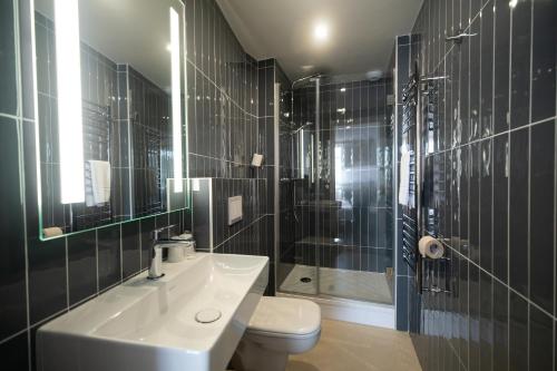 a bathroom with a sink and a toilet and a shower at Hôtel de la Baie in Crozon