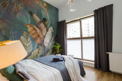 1 dormitorio con un mural de hojas en la pared en Woronicza Premium - Jungle Warsaw, en Varsovia