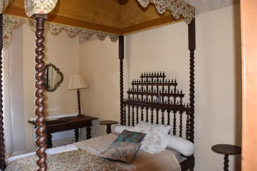 a bedroom with a canopy bed and a table at Prieuré du 17è dans l'Ardèche méridionale in Vagnas