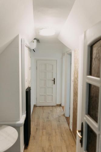 a hallway with a white door and a wooden floor at Palma Vendégház in Szeged