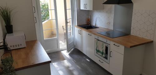 una cucina con armadi bianchi e piano di lavoro di NOUVEAU !!! Appartement cosy tout confort à deux pas de Strasbourg a Schiltigheim