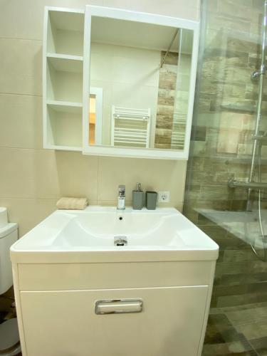 W łazience znajduje się biała umywalka i lustro. w obiekcie Ultracentral Modern Apartment w Kiszyniowie